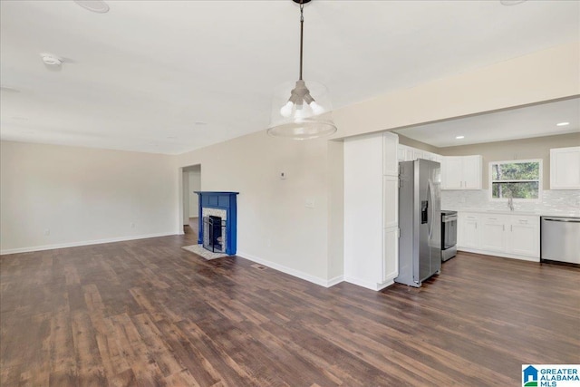 kitchen featuring white cabinets, a fireplace with flush hearth, appliances with stainless steel finishes, open floor plan, and light countertops