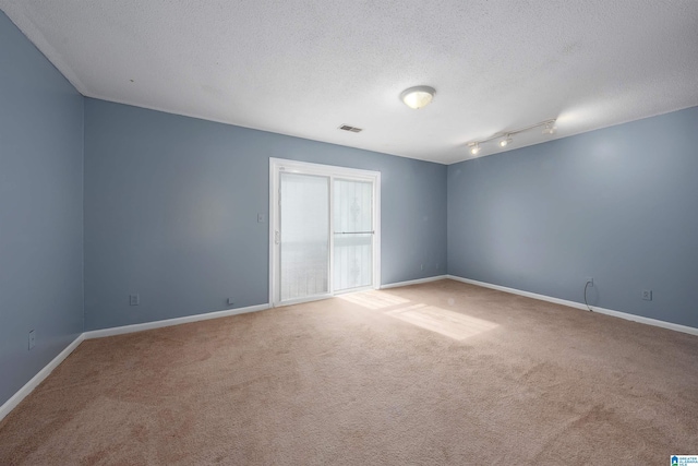 carpeted empty room featuring baseboards, visible vents, and a textured ceiling