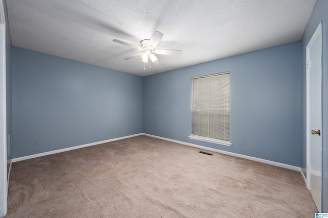 spare room featuring carpet floors, ceiling fan, visible vents, and baseboards