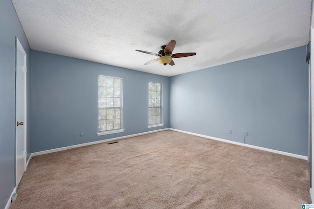 empty room featuring ceiling fan, a textured ceiling, visible vents, baseboards, and carpet