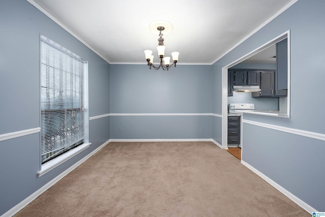 spare room featuring a chandelier, ornamental molding, carpet, and baseboards