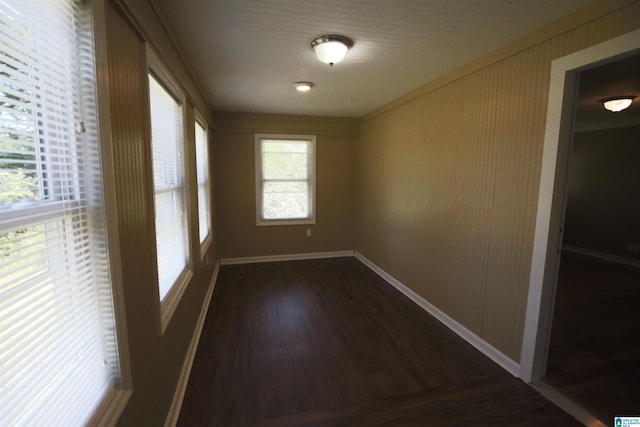 spare room with baseboards and dark wood-style flooring