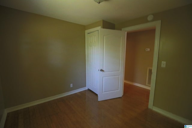 unfurnished bedroom featuring a closet, wood finished floors, visible vents, and baseboards