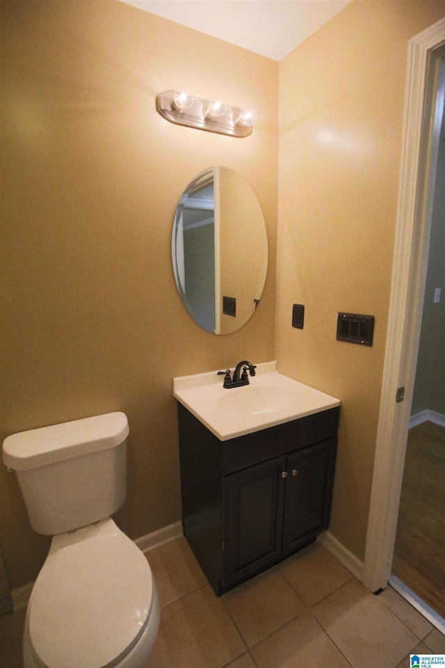 bathroom with toilet, tile patterned flooring, baseboards, and vanity