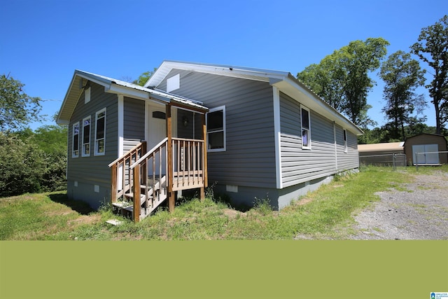 view of front facade featuring an outdoor structure, crawl space, metal roof, and a storage shed