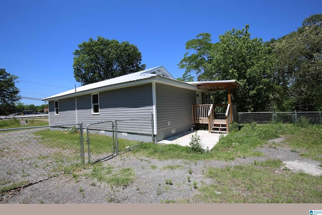 view of property exterior with crawl space, a gate, fence, and metal roof