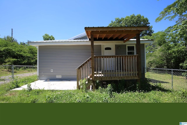 back of house featuring crawl space, a deck, fence, and metal roof