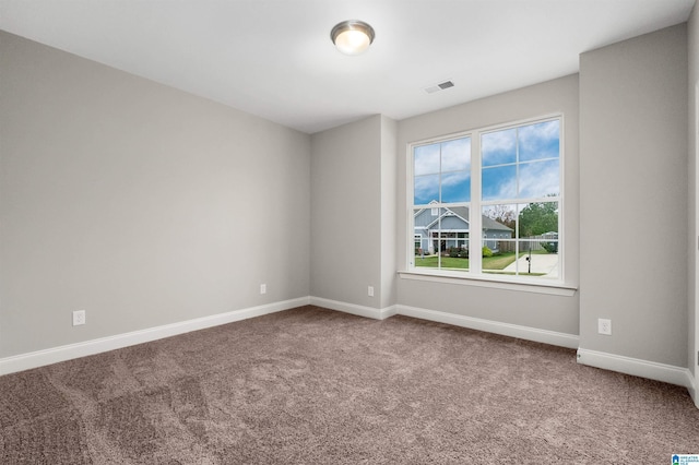 unfurnished room with carpet floors, visible vents, and baseboards