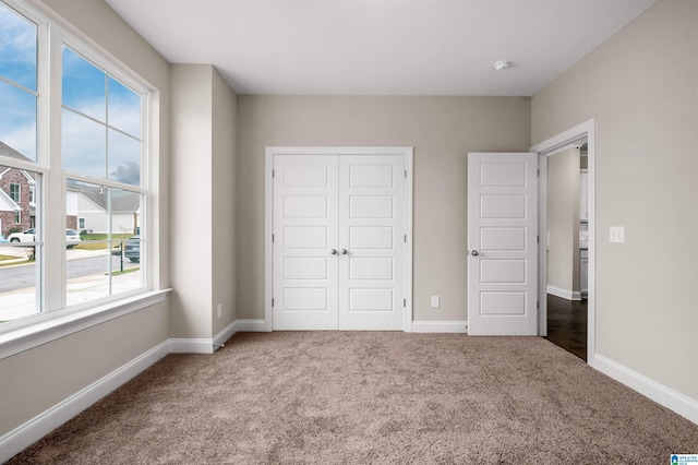 unfurnished bedroom with a closet, baseboards, and carpet flooring