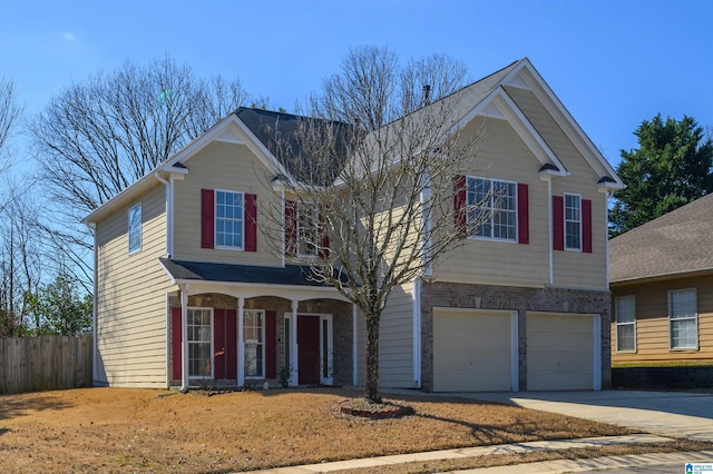 traditional-style home with driveway, brick siding, an attached garage, and fence