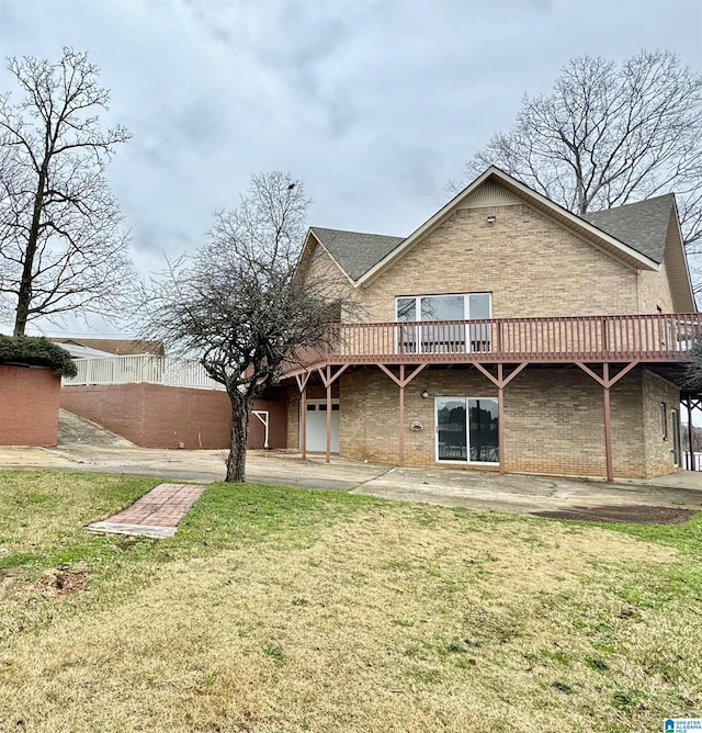 back of property featuring a deck, brick siding, and a lawn