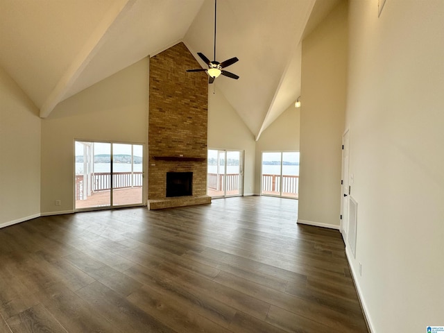 unfurnished living room featuring a ceiling fan, a brick fireplace, dark wood-style flooring, and a water view