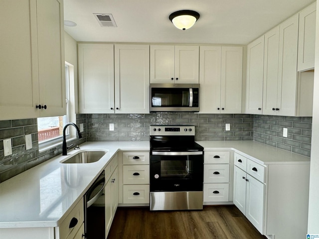 kitchen with visible vents, dark wood-style flooring, stainless steel appliances, white cabinetry, and a sink