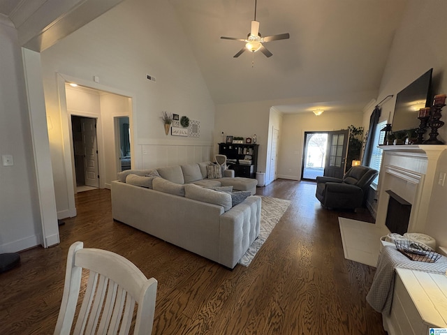 living room featuring high vaulted ceiling, dark wood-style flooring, a fireplace with raised hearth, and visible vents