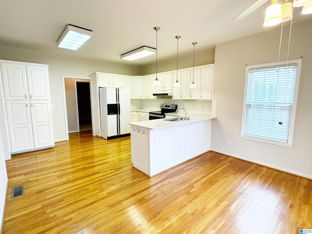 kitchen with under cabinet range hood, a peninsula, white refrigerator with ice dispenser, a sink, and stainless steel range with electric stovetop