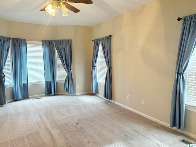 carpeted spare room featuring ceiling fan, visible vents, and baseboards