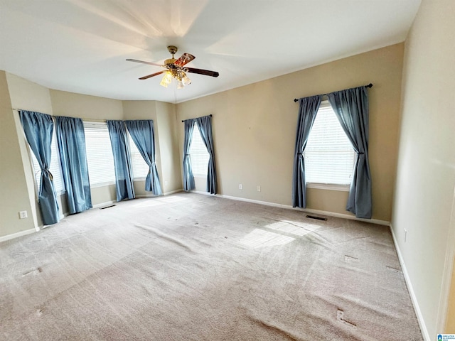 carpeted spare room with a ceiling fan, visible vents, and baseboards