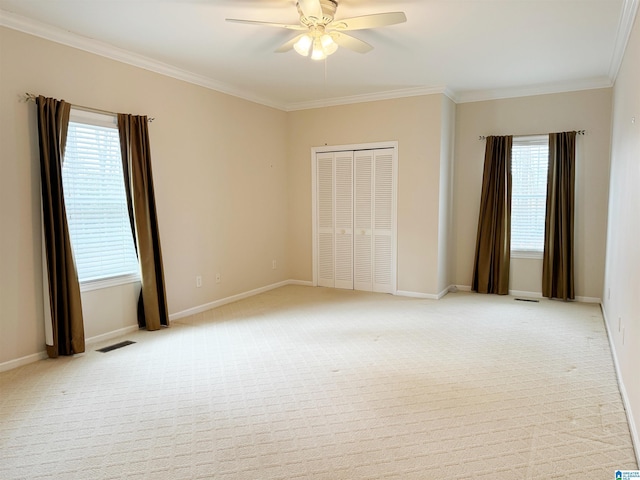 unfurnished bedroom with light carpet, ornamental molding, multiple windows, and visible vents