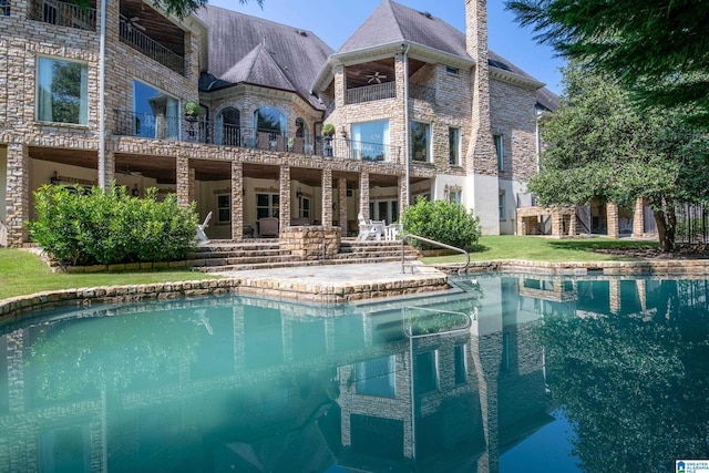 back of property with a chimney and an outdoor pool