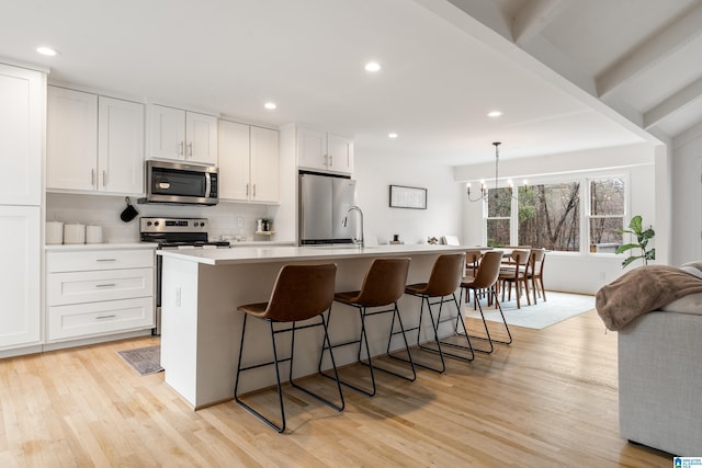 kitchen featuring an island with sink, white cabinetry, appliances with stainless steel finishes, and decorative backsplash