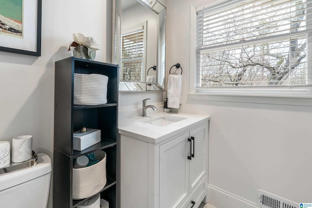 bathroom with a healthy amount of sunlight, visible vents, toilet, and vanity