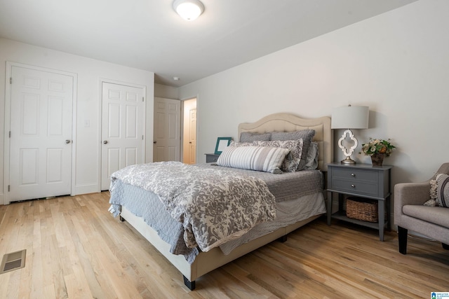 bedroom with light wood-style floors and visible vents