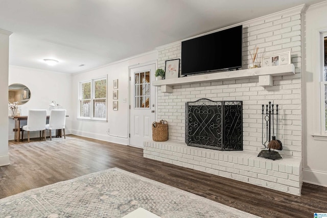 living area featuring ornamental molding, a brick fireplace, wood finished floors, and baseboards