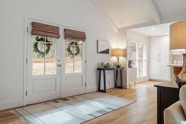 entryway featuring vaulted ceiling with beams, light wood-style flooring, baseboards, and french doors