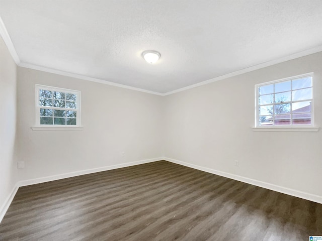 empty room featuring a textured ceiling, ornamental molding, dark wood finished floors, and baseboards