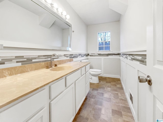 bathroom featuring toilet, vanity, and visible vents