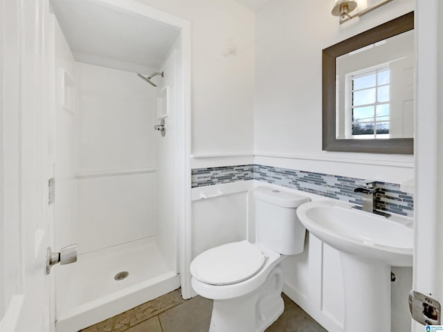 bathroom featuring toilet, a wainscoted wall, a shower stall, and tile patterned flooring