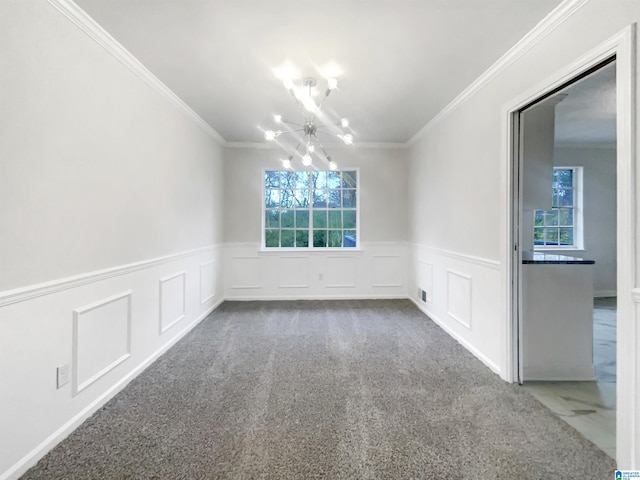 spare room featuring a chandelier, a healthy amount of sunlight, crown molding, and carpet floors