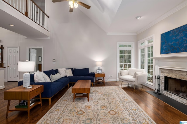 living area featuring high vaulted ceiling, a stone fireplace, dark wood-style flooring, baseboards, and ornamental molding