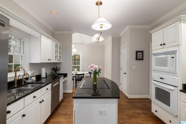 kitchen with white appliances, a kitchen island, white cabinets, and a sink