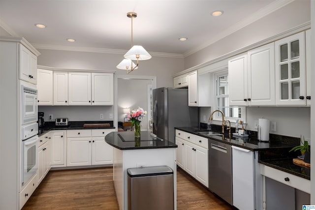 kitchen with stainless steel appliances, dark countertops, glass insert cabinets, white cabinetry, and a kitchen island