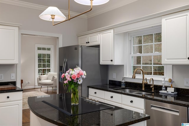 kitchen featuring appliances with stainless steel finishes, white cabinetry, a sink, and decorative light fixtures