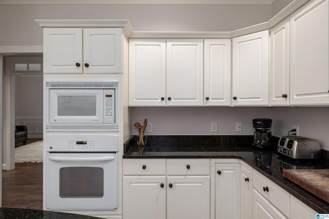 kitchen with white appliances, white cabinets, and dark stone countertops