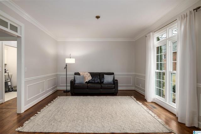 sitting room with wainscoting, ornamental molding, dark wood finished floors, and a decorative wall