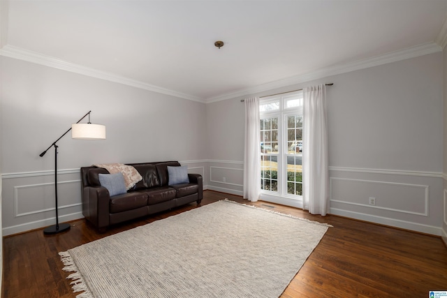 living room with crown molding, wainscoting, dark wood finished floors, and a decorative wall