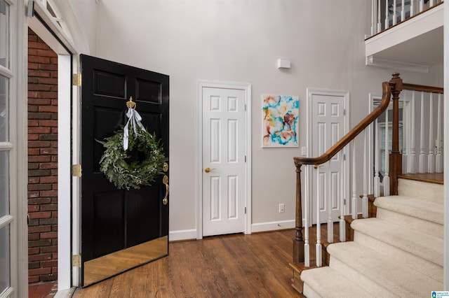 foyer entrance featuring a towering ceiling, stairway, baseboards, and dark wood-type flooring