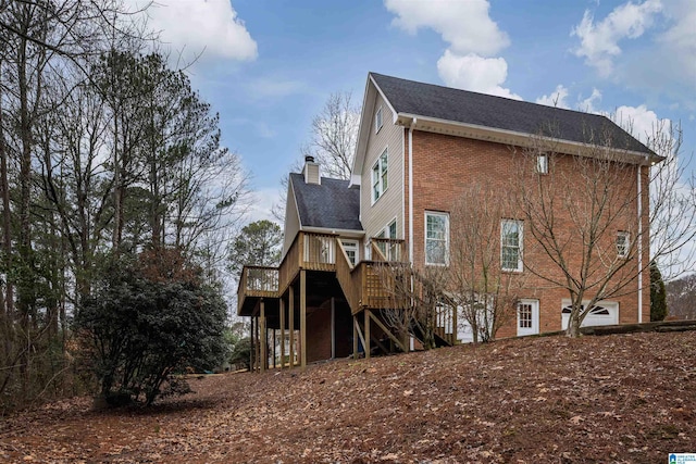 back of property featuring stairs, brick siding, a chimney, and a deck