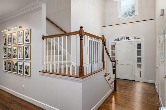 foyer entrance with crown molding, dark wood finished floors, stairs, and baseboards