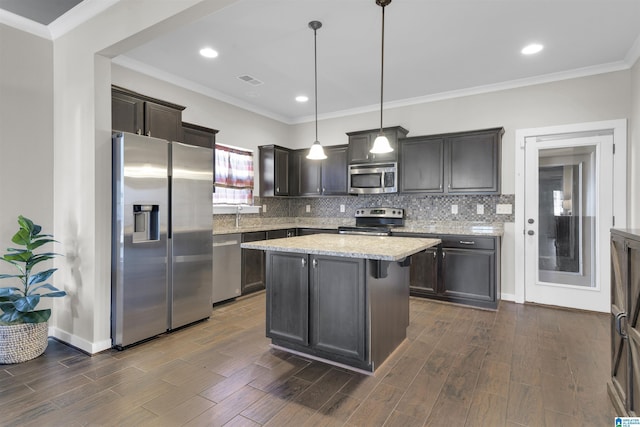 kitchen with dark wood-style flooring, a kitchen island, appliances with stainless steel finishes, backsplash, and decorative light fixtures