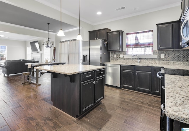 kitchen featuring a breakfast bar area, stainless steel appliances, visible vents, hanging light fixtures, and open floor plan