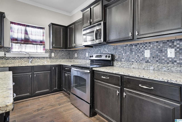 kitchen with tasteful backsplash, dark wood-style flooring, light stone countertops, stainless steel appliances, and crown molding