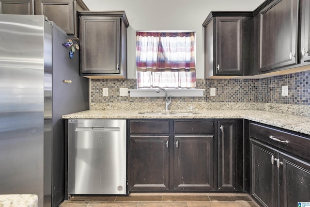 kitchen with stainless steel appliances, backsplash, a sink, and dark brown cabinetry