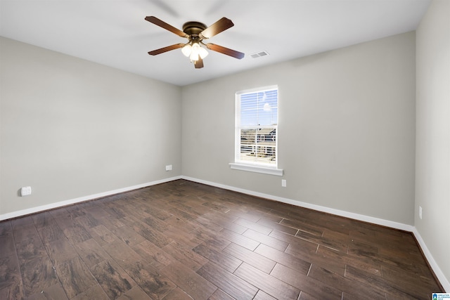 empty room with dark wood-style floors, visible vents, a ceiling fan, and baseboards