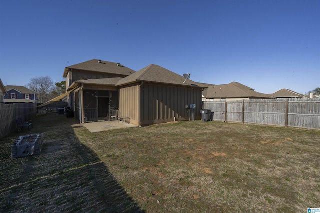 back of property with a fenced backyard, roof with shingles, a yard, a patio area, and board and batten siding