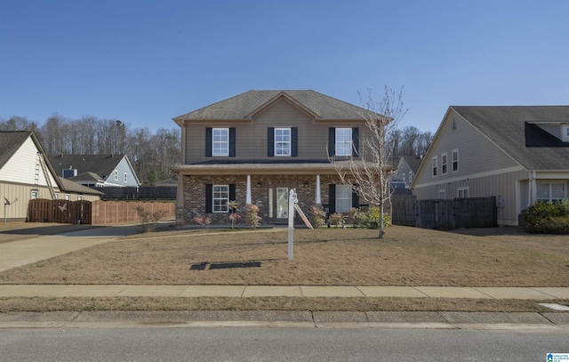 view of front facade featuring covered porch, brick siding, a front yard, and fence