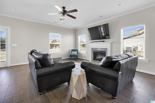 living room with baseboards, ornamental molding, a tiled fireplace, and wood finish floors